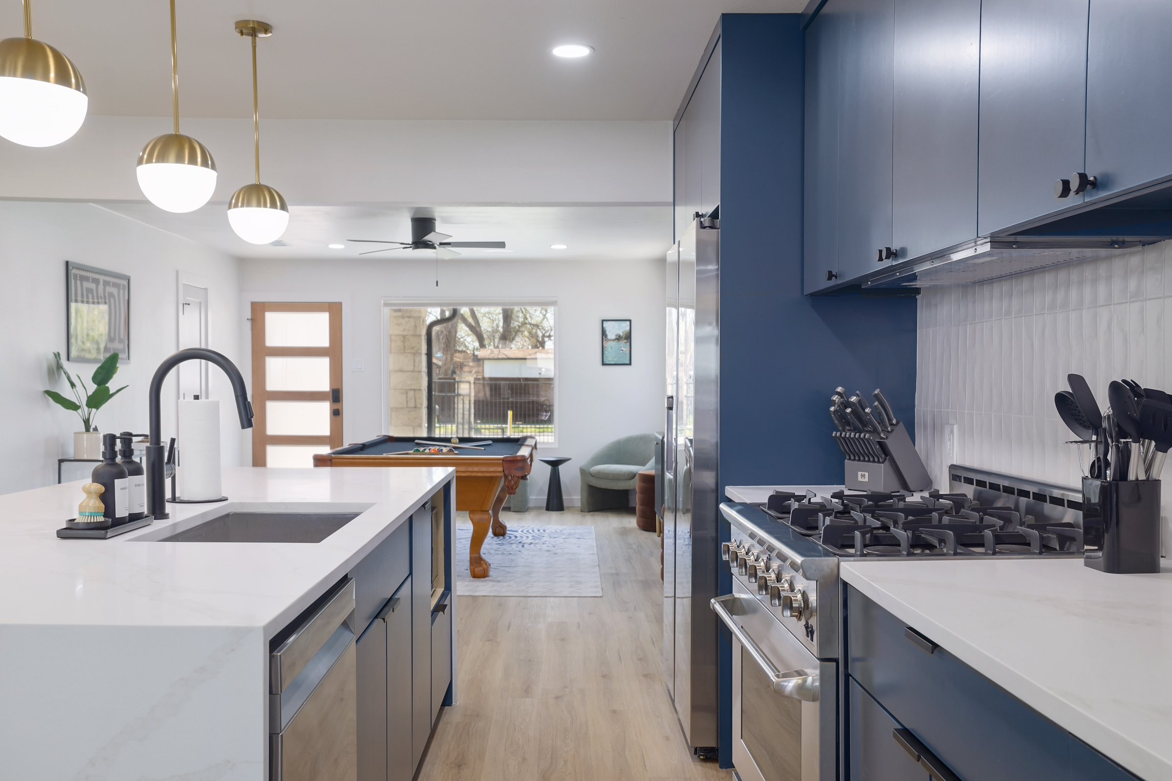 Austin East Bird · Modern kitchen with navy cabinets, quartz island, and brass pendants