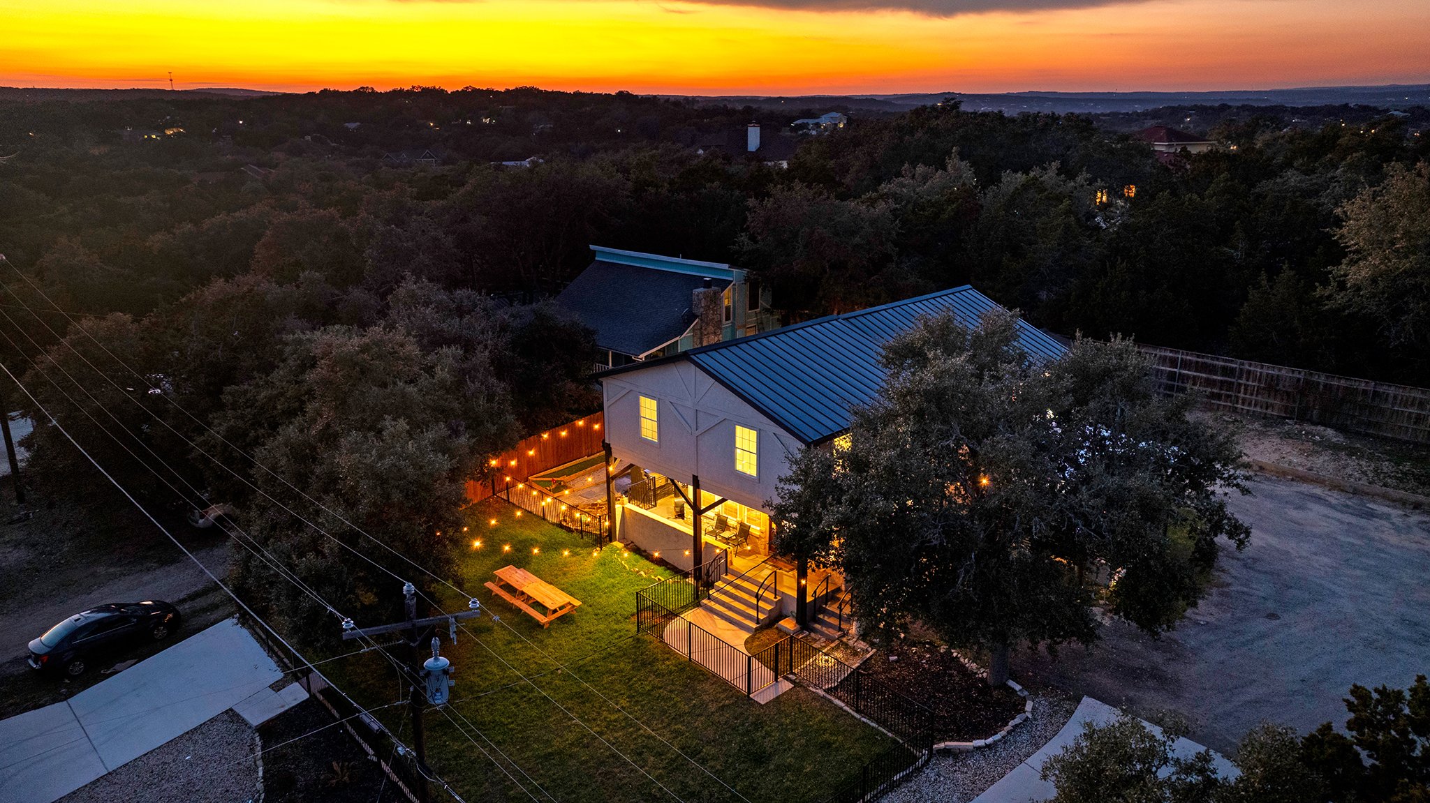 Cosmic Cowboy Retreat · Aerial view of two-story home at sunset overlooking hill country