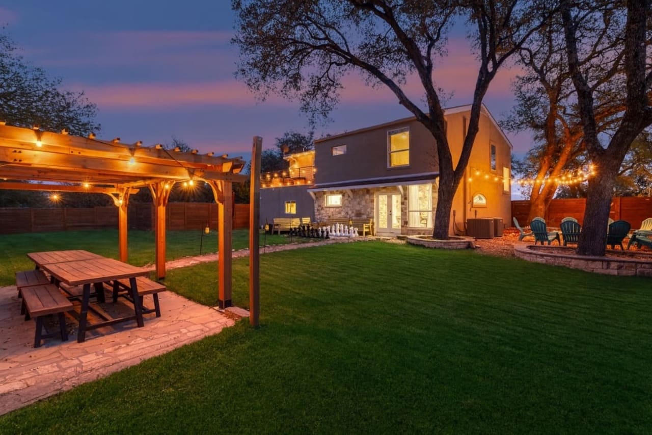 Dragonfly Escape · Backyard at dusk with pergola, string lights, and fire pit area