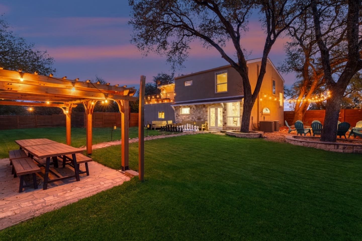 Dragonfly Escape · Backyard at dusk with pergola, string lights, and fire pit area