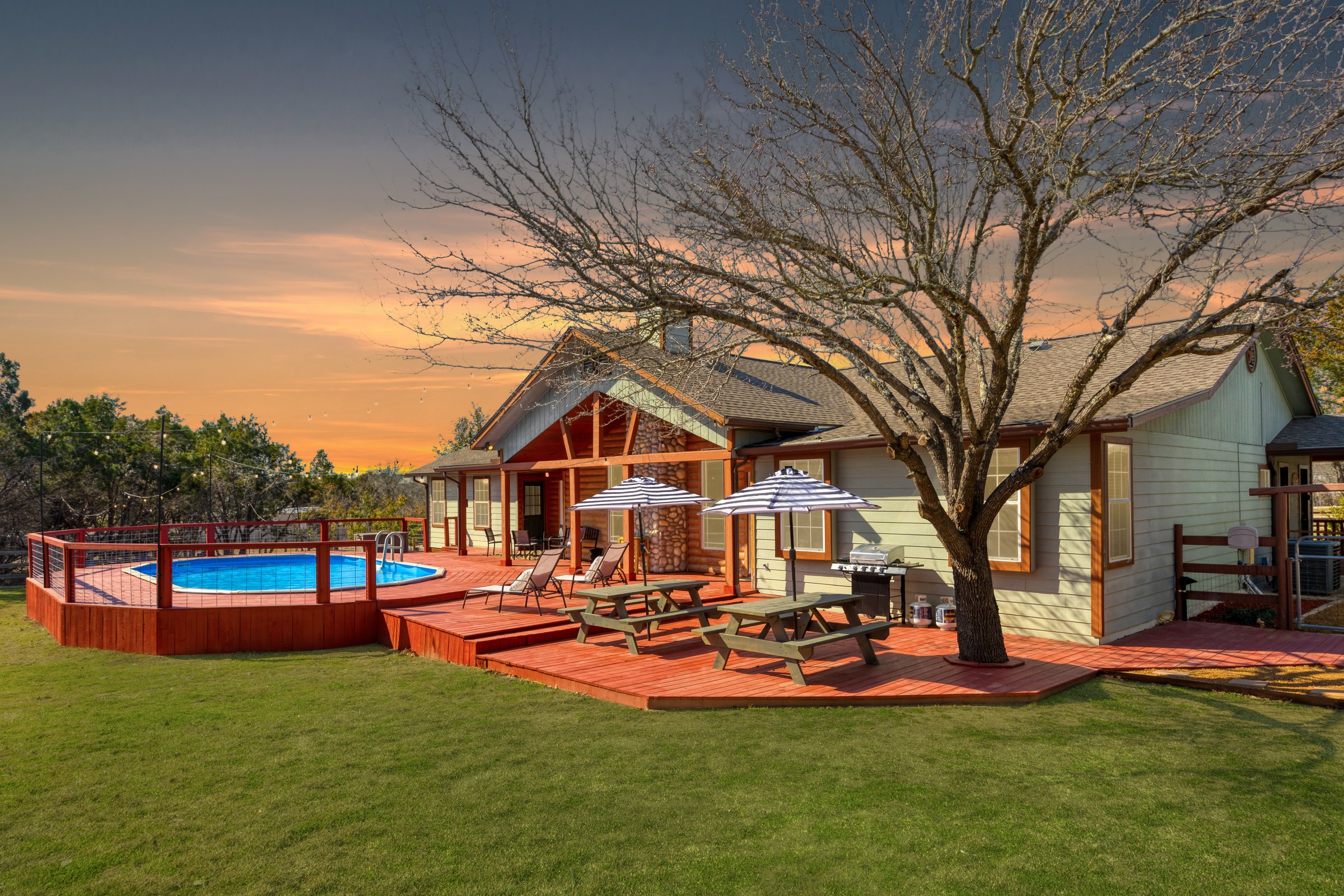 Fitzhugh Lodge · Cabin back deck at sunset with above-ground pool and picnic tables