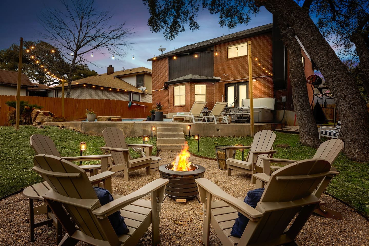 Shady Oak Retreat backyard fire pit with six Adirondack chairs at dusk