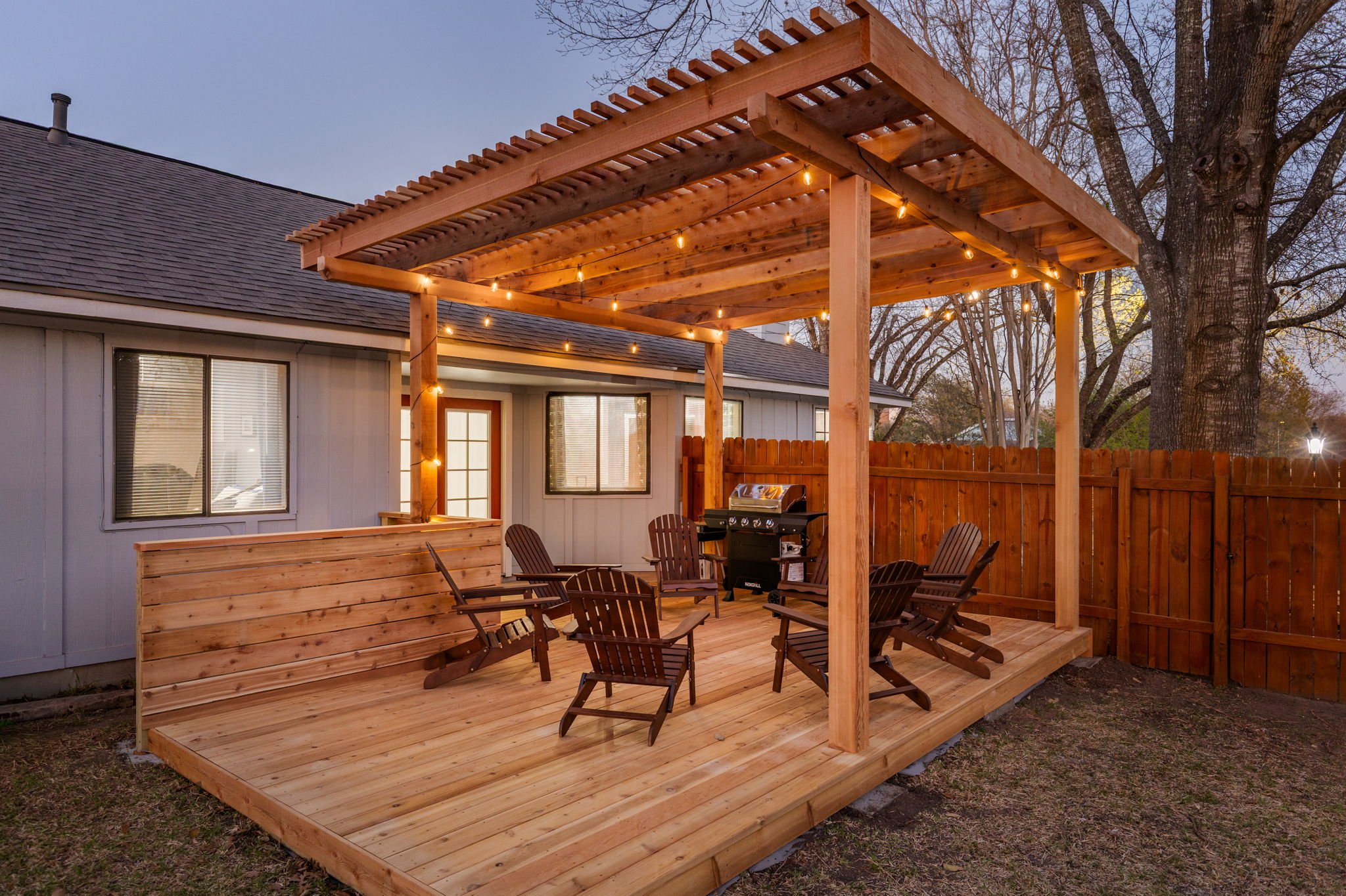 Vinyl Nest backyard cedar deck with pergola and string lights at dusk